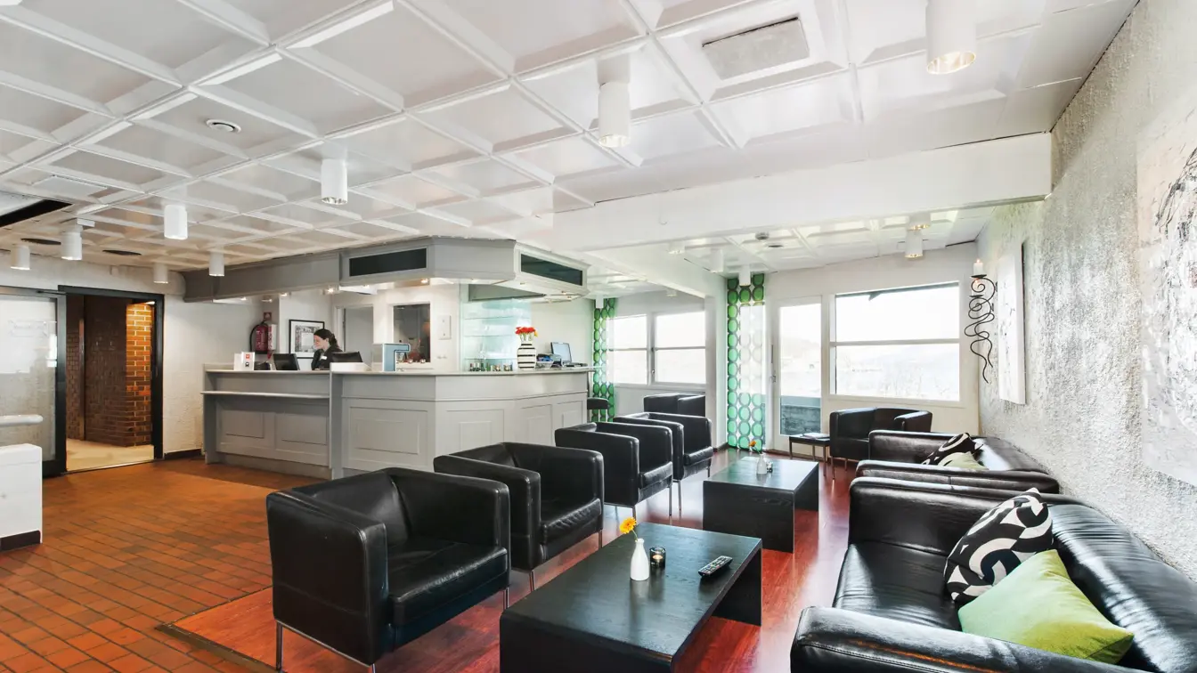 Lobby og resepsjonsområdet med mursteinsgulv og sorte sittemøbler hos Thon Hotel Sandnes