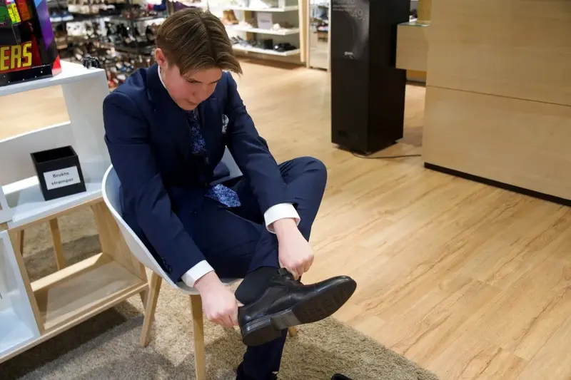 gutt i dress tar på seg dressko