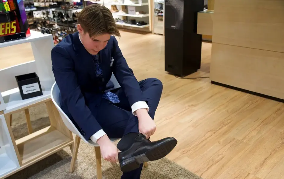 gutt i dress tar på seg dressko