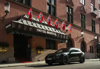 Mørk bil står foran fasaden til Hotel Bristol i solskinn