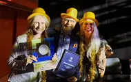 Tre ansatte på Oasen Storsenter har på seg gule hatter og holder diplom fra prisutdeling på kjøpesenterkonferanse.