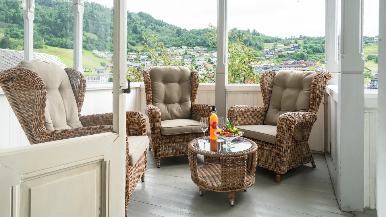 Veranda med peoner på bordet, eplemost i flaske og verandastoler på Thon Hotel Sandven i Norheimsund