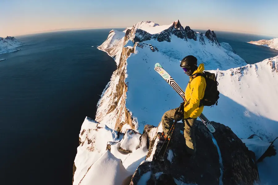 Mann i turklær står på toppen av et fjell 