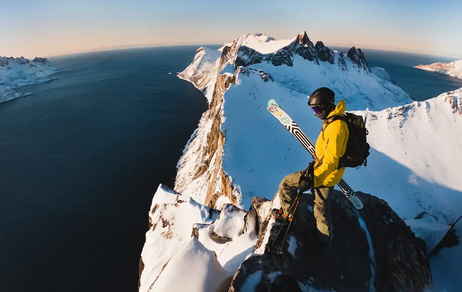 Mann i turklær står på toppen av et fjell 