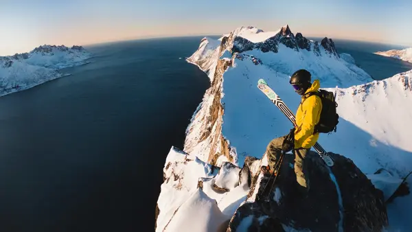 Mann i turklær står på toppen av et fjell 