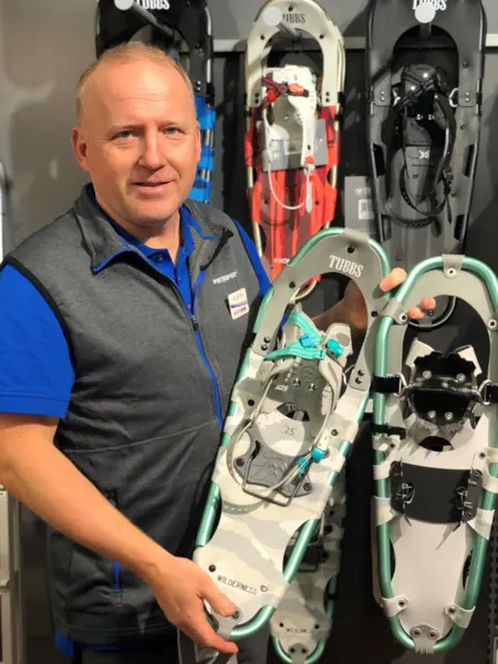 ansatt hos intersport viser frem utvalg av truger