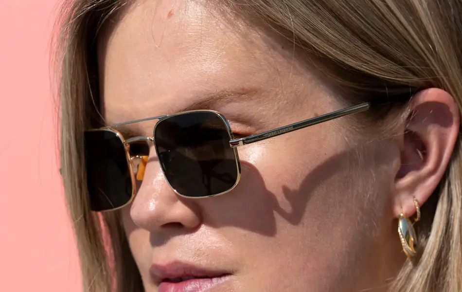 Jente med lyst hår og solbriller med gullramme