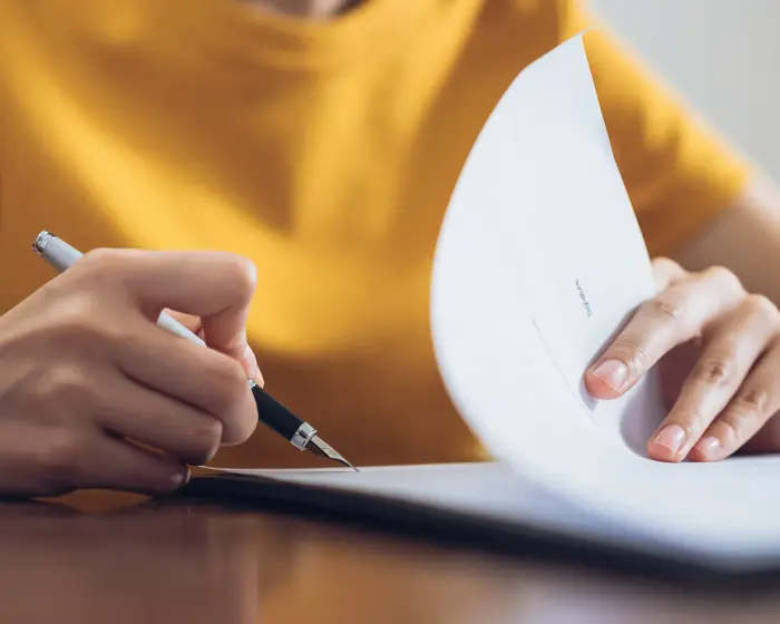 Woman signing document and hand holding pen putting signature at paper, order to authorize their rights.
