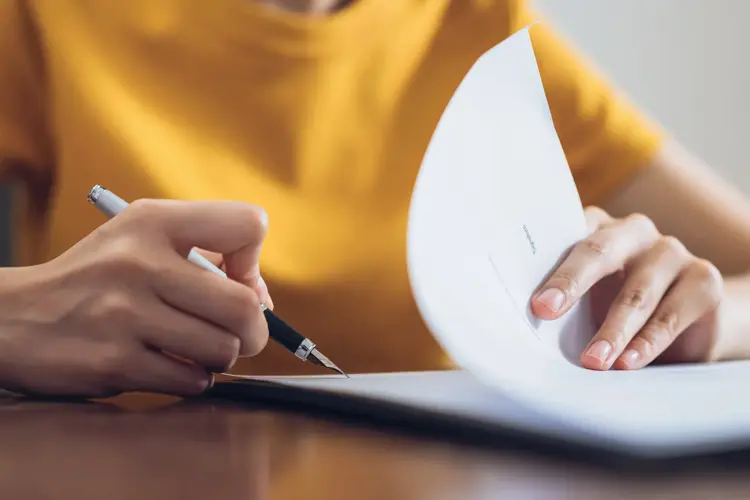 Woman signing document and hand holding pen putting signature at paper, order to authorize their rights.