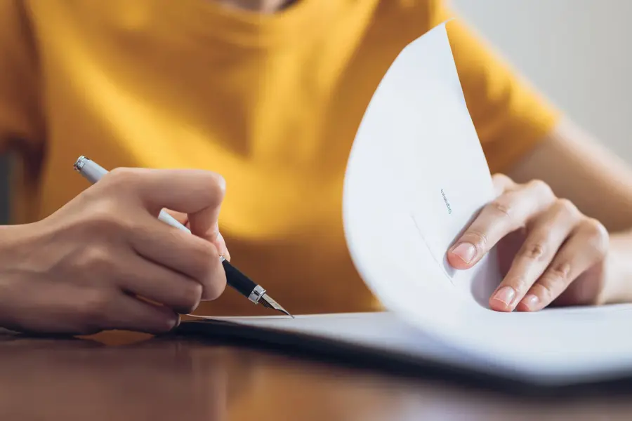 Woman signing document and hand holding pen putting signature at paper, order to authorize their rights.
