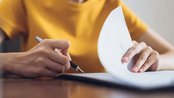 Woman signing document and hand holding pen putting signature at paper, order to authorize their rights.
