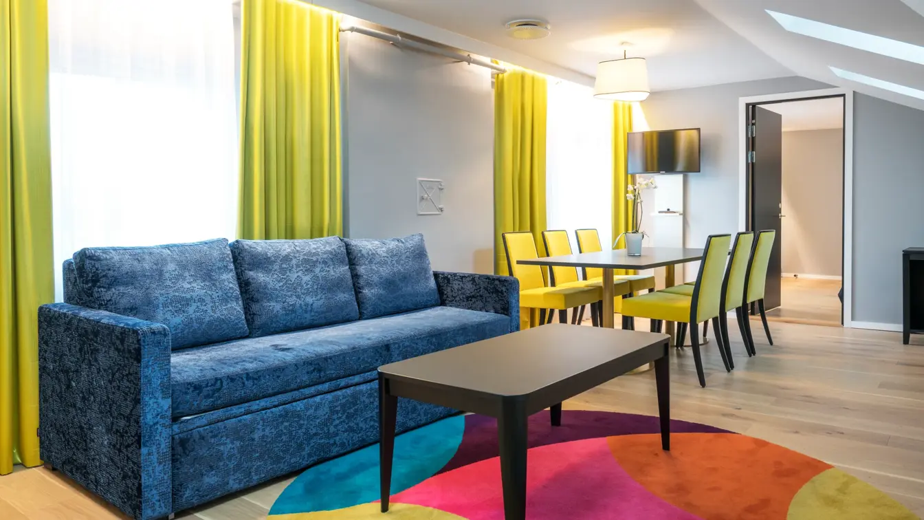 Sofa og spisebord med seks sitteplasser med sikt inn til soverommet på suite på Thon Hotel Spectrum i Oslo sentrum