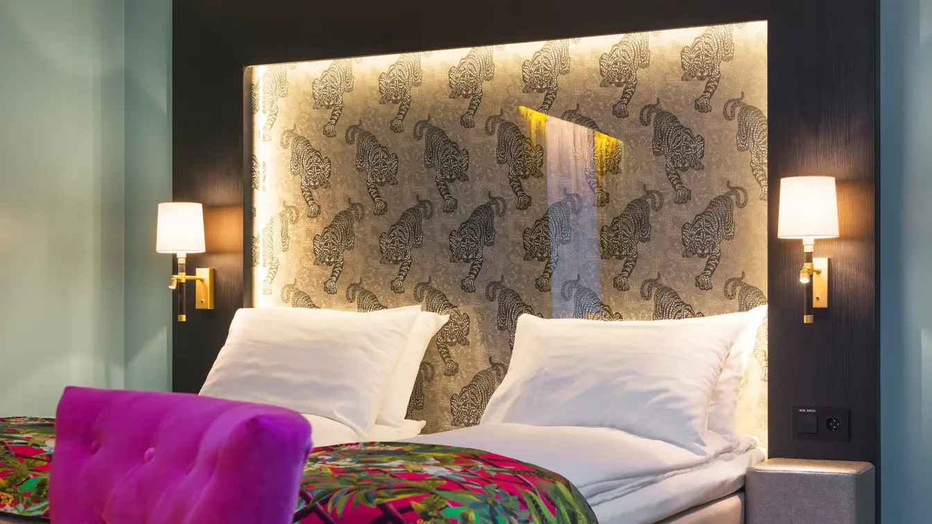 Dobbeltseng med mønstrede sengeteppe og lilla stol på buisness room på Thon hotel Terminus i Oslo sentrum nær Jernbanetorget