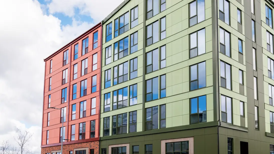 Fasade til hotellet med grønne og rød vegger med bilvei foran.