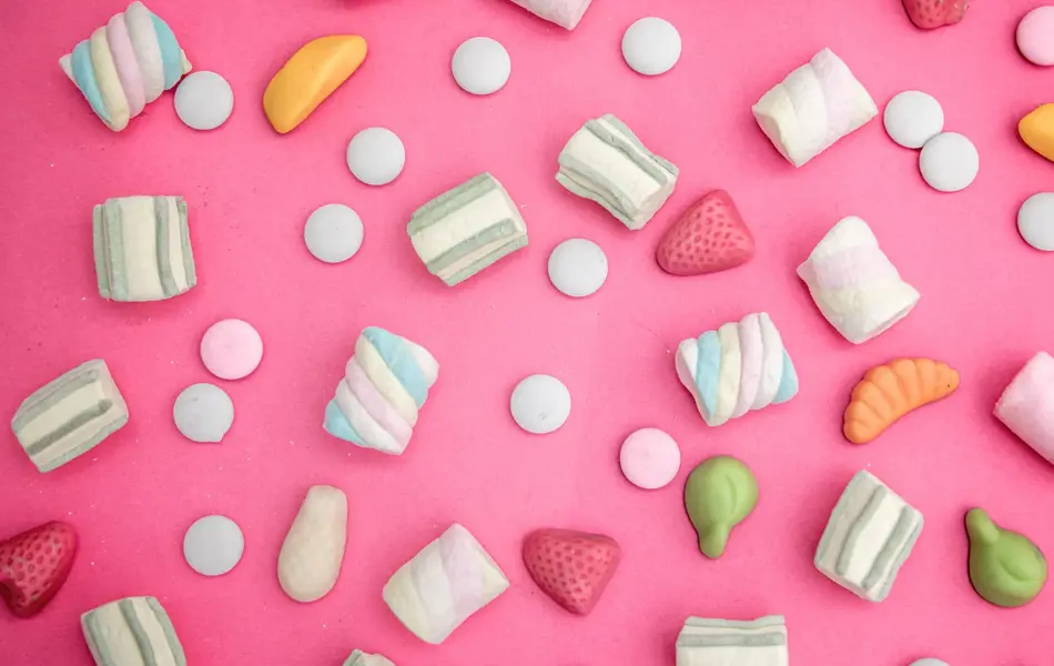 Godteri strødd omkring på rosa bakgrunn