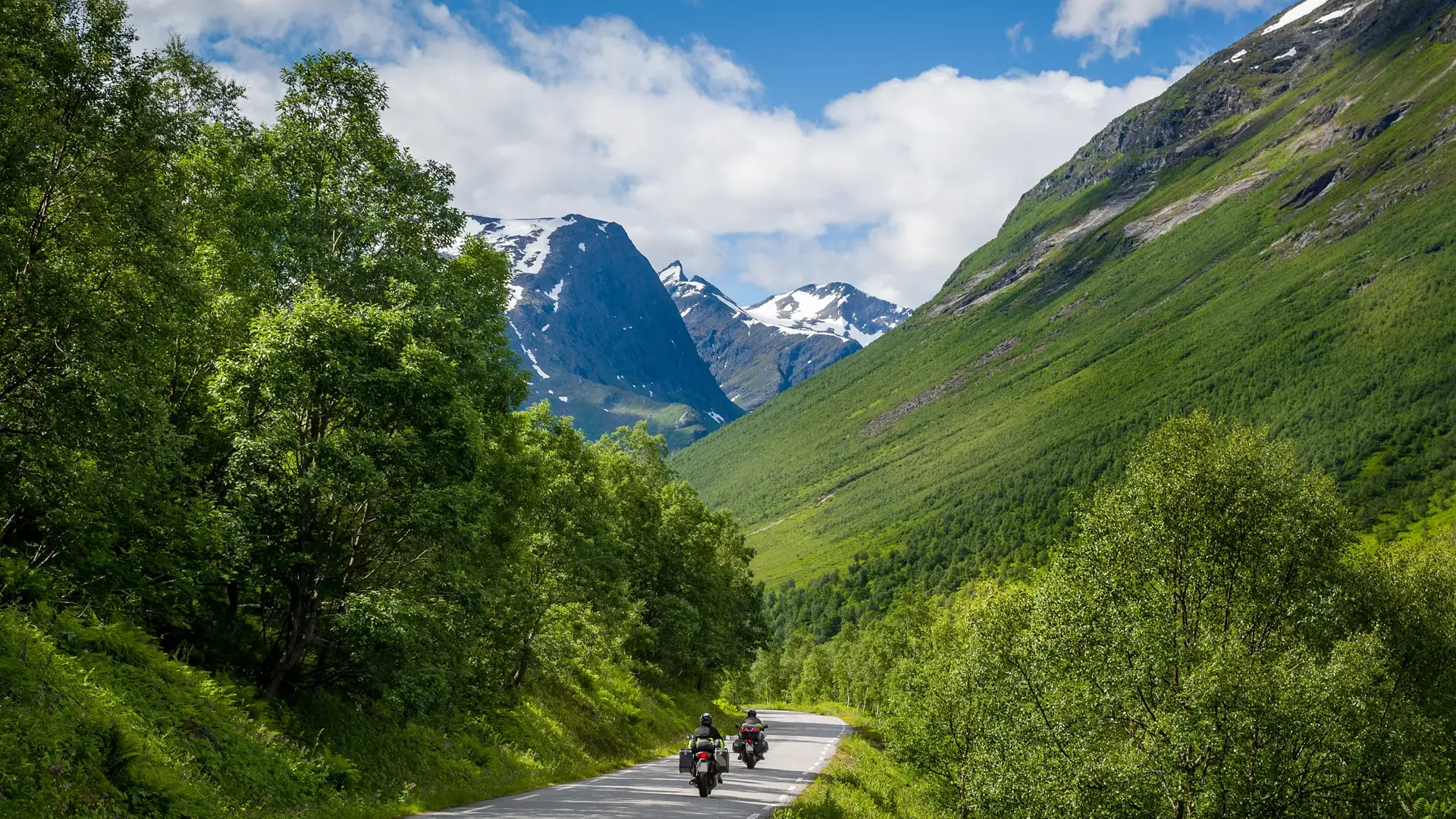 Bilde av to motorsyklister på veien med fjell i bakgrunnen