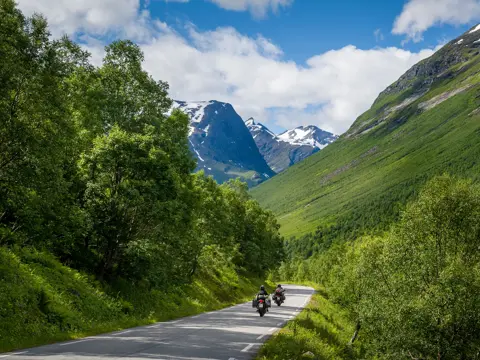 Bilde av to motorsyklister på veien med fjell i bakgrunnen
