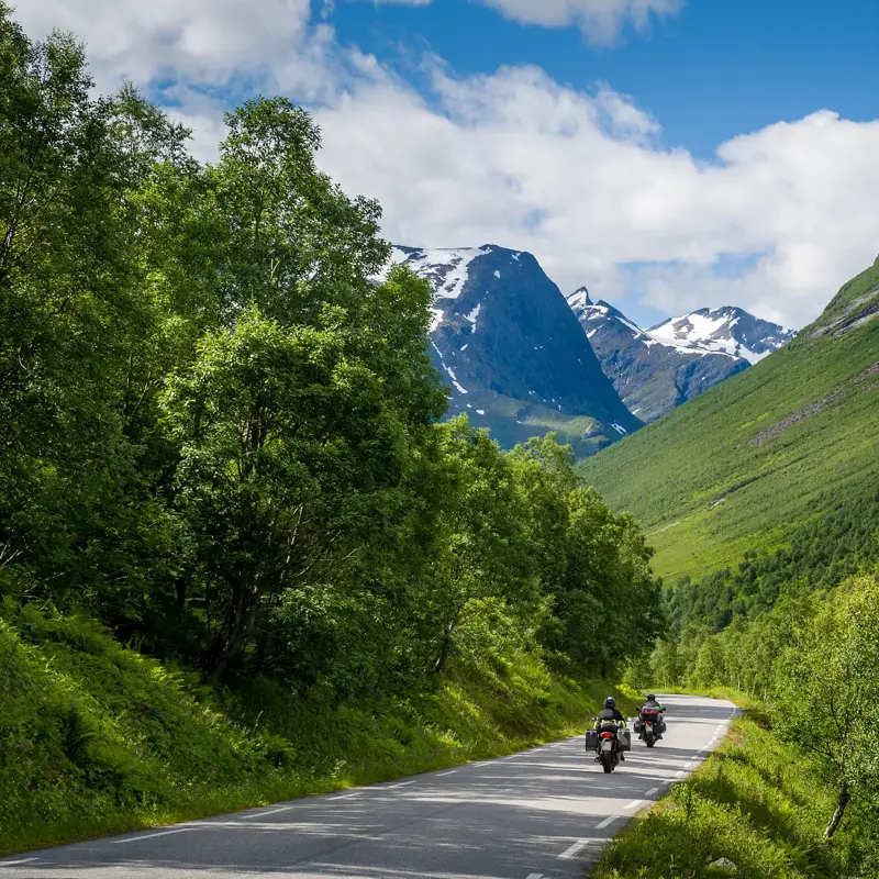 Bilde av to motorsyklister på veien med fjell i bakgrunnen
