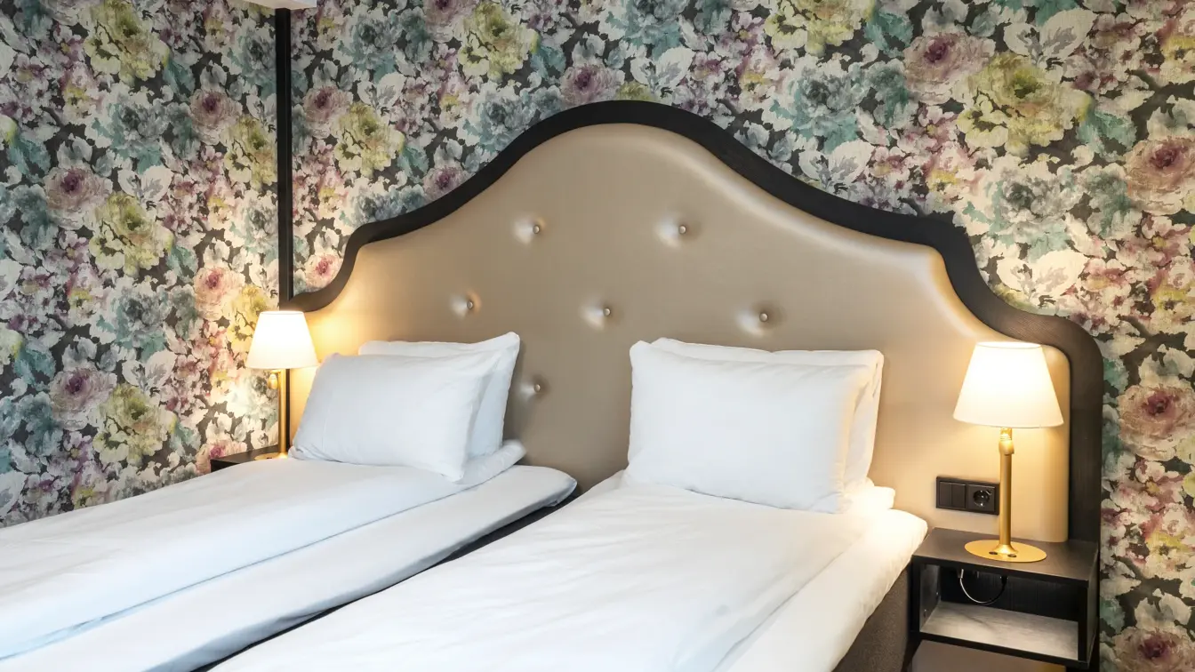 To enkeltsenger, blomstret tapet bak sengene på twin room på Thon Hotel Cecil i Oslo sentrum