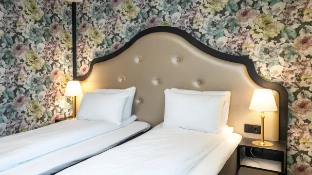 To enkeltsenger, blomstret tapet bak sengene på twin room på Thon Hotel Cecil i Oslo sentrum