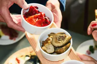 Små serveringsskåler med tapasretter på et serveringsbrett.