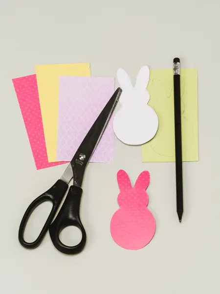 Fire forskjellige ark, to utklippede påskeharer, en saks og en penn