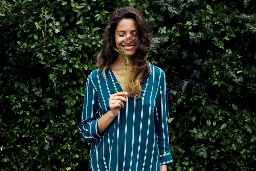 Dame holder plante og smiler 