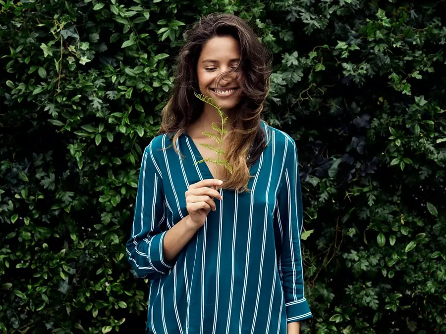 Dame holder plante og smiler 