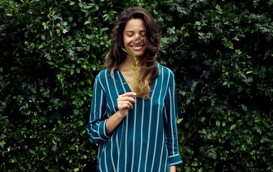 Dame holder plante og smiler 