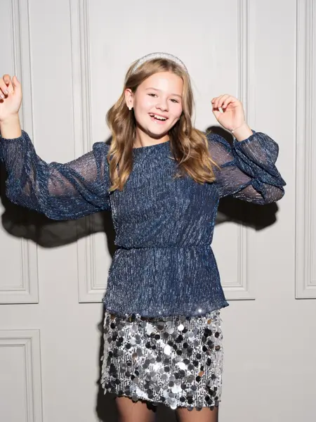 Jente i glitrende topp og paljettskjørt som ler 