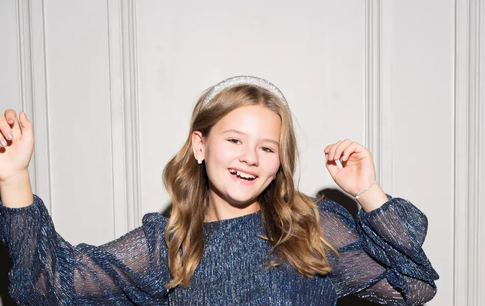 Jente i glitrende topp og paljettskjørt som ler 