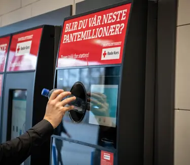 En hånd strekker seg mot pantemaskinen for å pante en flaske