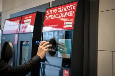 En hånd strekker seg mot pantemaskinen for å pante en flaske