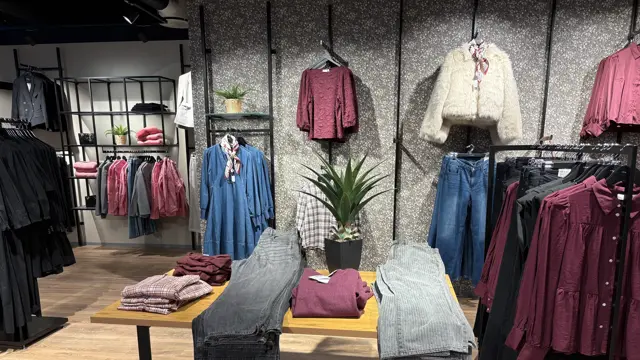 Klær som henger på vegg og ligger på bord i fargene, ola, sort, burgunder og creme