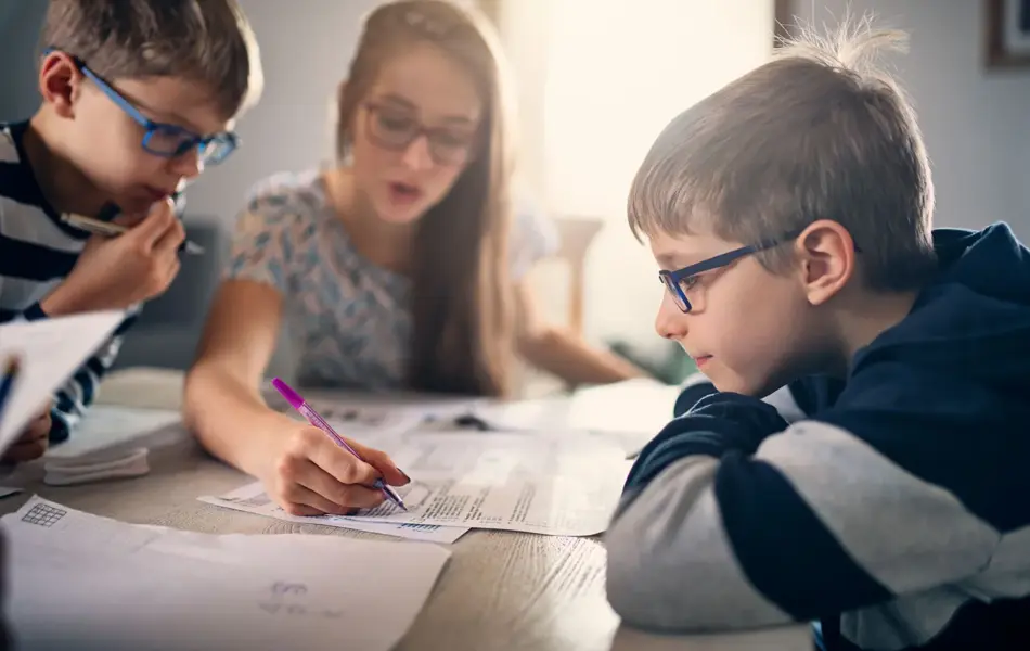 Tre barn med briller som gjør leksene sine