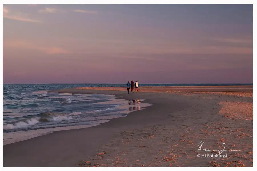 3 personer som går på en strand