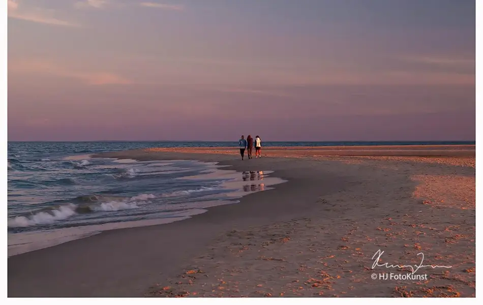 3 personer som går på en strand