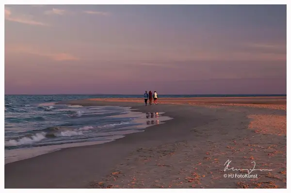 3 personer som går på en strand