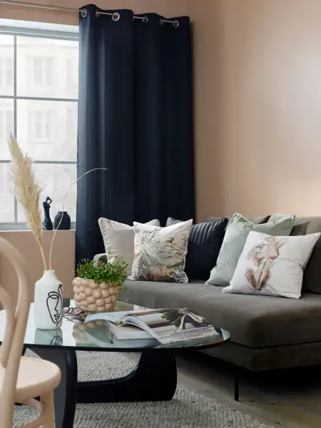 grå sofa med fargerike puter og blå gardiner