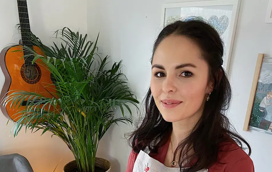 Kvinne som holder opp et bakebrett med et spiselig juletre laget av boller