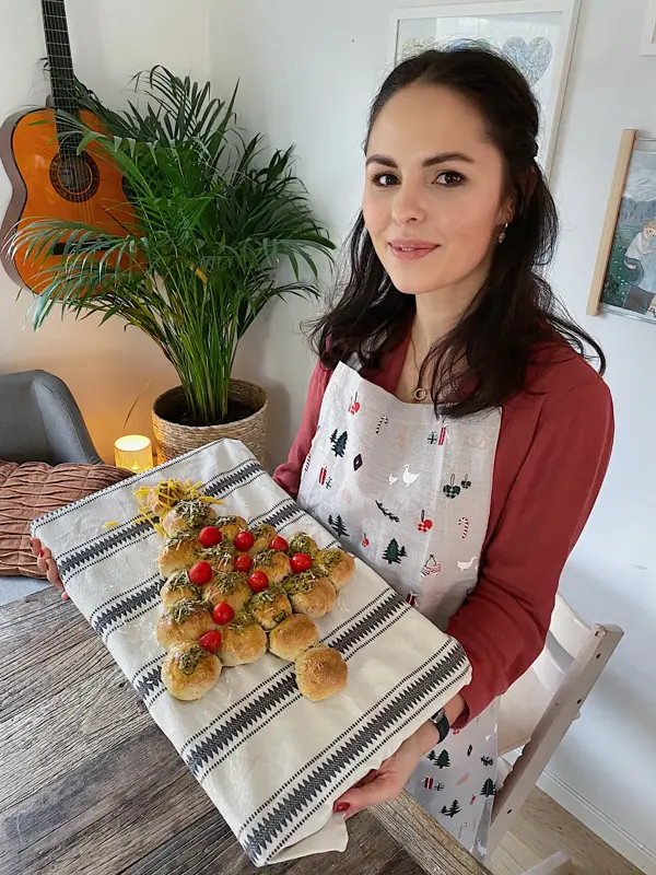 Kvinne som holder opp et bakebrett med et spiselig juletre laget av boller