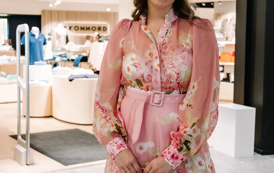 dame i kjole står foran butikk