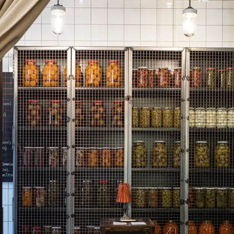 Hyller med krukker med ulike syltede grønnsaker