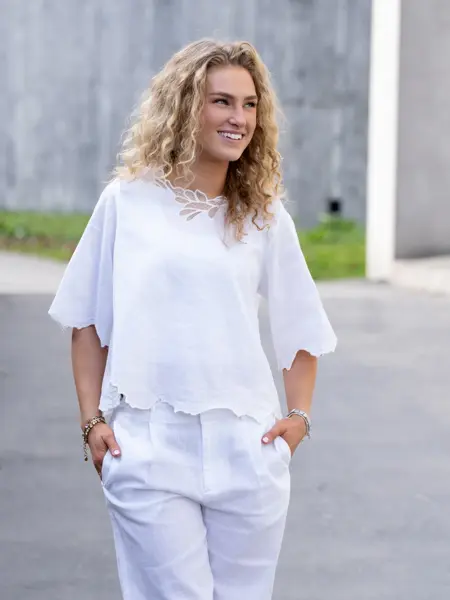 Ung dame i hvit lintopp og bukse.