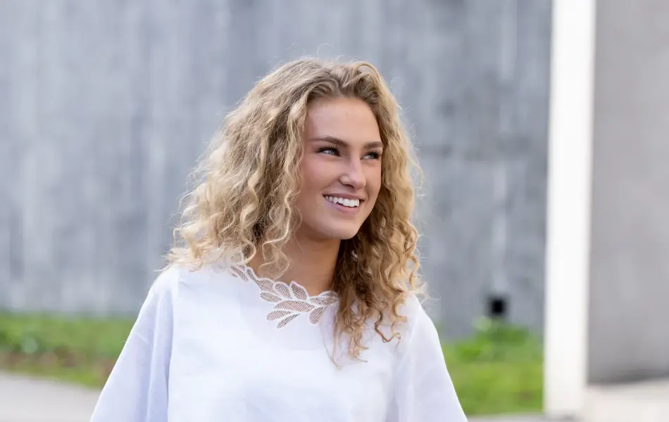 Ung dame i hvit lintopp og bukse.