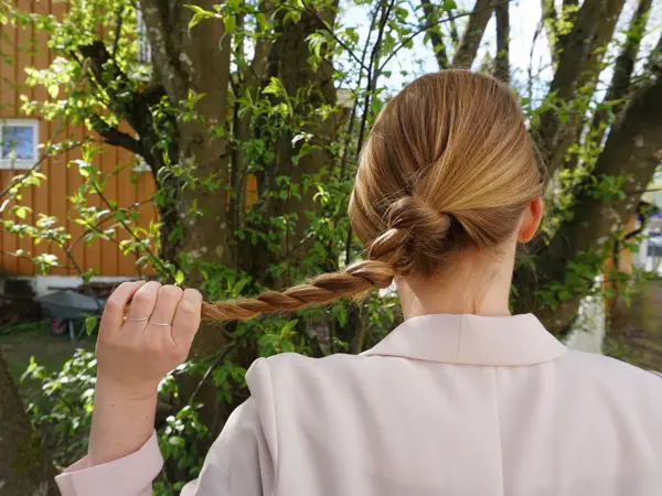 Kvinne som holder en tvinnet flette, sett bakfra