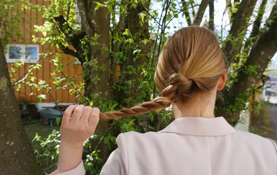 Kvinne som holder en tvinnet flette, sett bakfra
