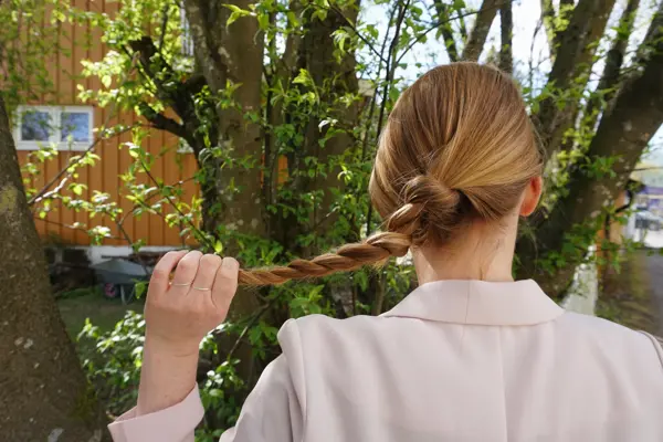 Kvinne som holder en tvinnet flette, sett bakfra