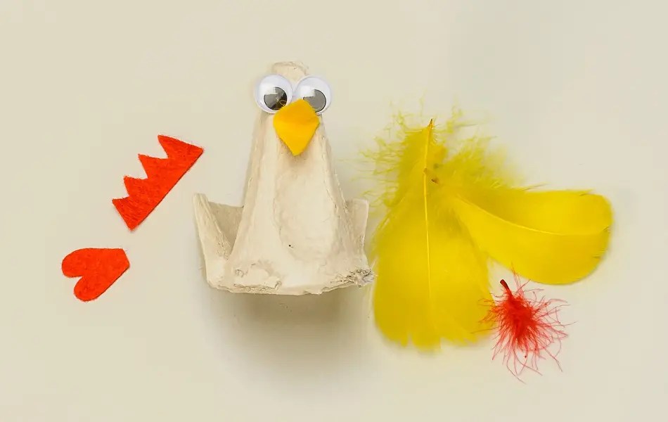 En eggekartong omgjort til en høne med øyne og nebb, resten av utstyret ligger ved siden av 
