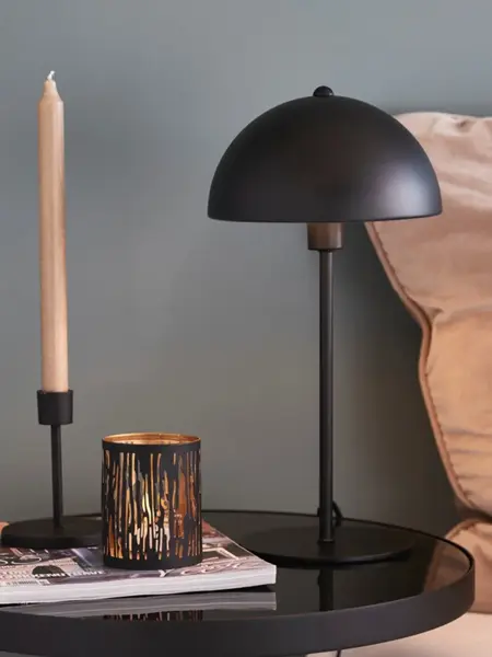 Bordlampe på et bord sammen med lysestake og telysholder